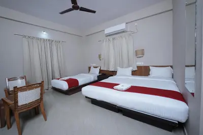 a hotel room with two beds and a ceiling fan at DREAMS AIRPORT RESIDENCY in Nedumbassery