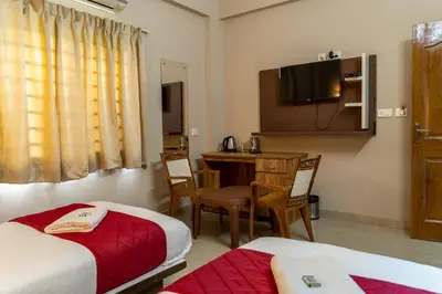a hotel room with two beds and a desk and a television at DREAMS AIRPORT RESIDENCY in Nedumbassery