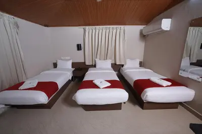a room with three beds with red and white sheets at DREAMS AIRPORT RESIDENCY in Nedumbassery