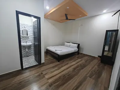 a room with a bed and a mirror and a sink at Comfort Cove Apartments in Mysore