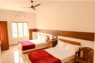 a bedroom with two beds and a ceiling fan at sevens residency in Sultan Bathery