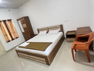a bedroom with a bed and a desk and a chair at sevens residency in Sultan Bathery