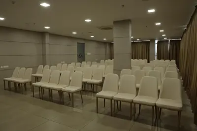 a room with rows of white chairs in it at Dreamotel Luxury Suites in Kanjikode