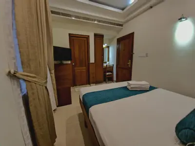 a bedroom with a white bed with a blue blanket at Vishnu Inn in Guruvāyūr