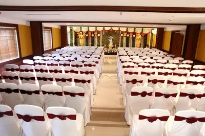 a room filled with white chairs with red bows at Vishnu Inn in Guruvāyūr