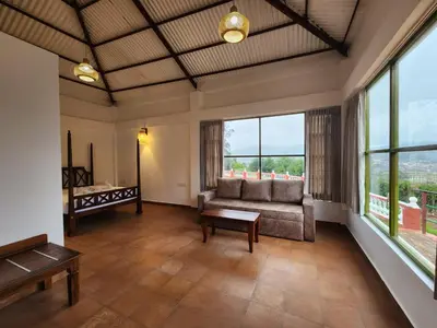 a living room with a couch and large windows at Welbeck Vintage By Oxygen Resorts in Ooty