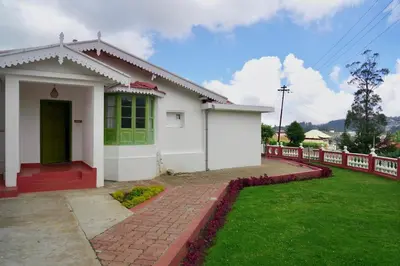 a small white house with a red fence at Welbeck Vintage By Oxygen Resorts in Ooty