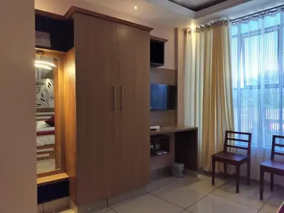 a bedroom with a large wooden cabinet with a desk at IvyArk Residency in Pinangode