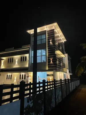 a large house with a fence in front of it at night at Furnished 2 BHK Family Apartments near Triprayar Shree Rama Temple - Beevees Homes Thriprayar in Thanniyam