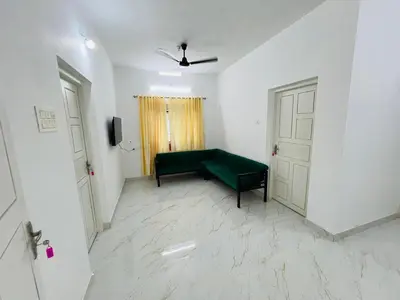 a living room with a green couch and a door at Furnished 2 BHK Family Apartments near Triprayar Shree Rama Temple - Beevees Homes Thriprayar in Thanniyam