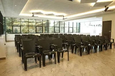 a large room with black chairs and windows at Bluemist Resorts in Athirappilly