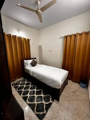 a bedroom with a bed with brown curtains and a rug at DEEYA Home Stay - A Luxury Family Guest House in Mysore