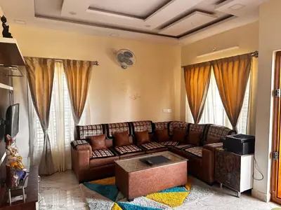 a living room with a brown leather couch and curtains at DEEYA Home Stay - A Luxury Family Guest House in Mysore