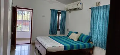 a bedroom with a bed with blue curtains and a window at SHI's Alaya 3BHk Villa in Coimbatore, near Railway station in Pīlamedu