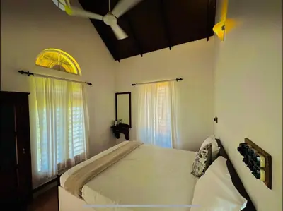 a bedroom with a large bed and two windows at THALIMALA BUNGALOW in Vythiri