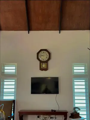 a clock hanging on a wall with two windows at THALIMALA BUNGALOW in Vythiri