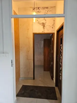 a hallway with a door leading into a room with marble walls at Yogis Inn in Kozhikode