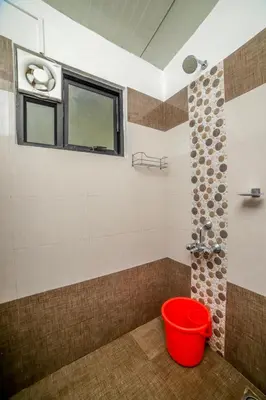 a bathroom with a red bucket and a window at Shola Gardens , Kotagiri in Kotagiri