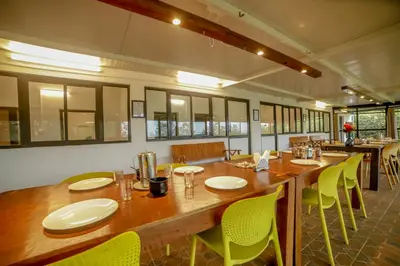 a dining room with a large wooden table and chairs at Shola Gardens , Kotagiri in Kotagiri