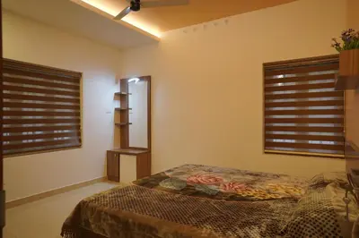 a bedroom with two windows and a bed in it at Luxury Homes - Cochin Airport - Nedumbassery in Angamali