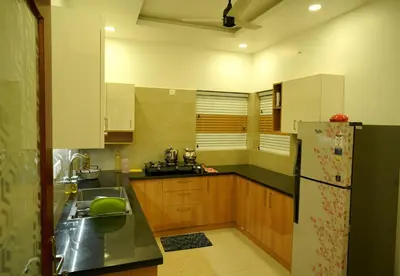 a kitchen with wooden cabinets and a refrigerator at Luxury Homes - Cochin Airport - Nedumbassery in Angamali