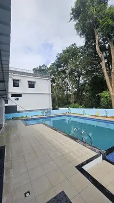 a swimming pool in front of a building at Wayanad Palace in Ambalavayal
