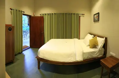a bedroom with a bed with white sheets and yellow pillows at SylVan Resort in Wayanad