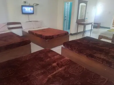 a room with four beds and a tv on a wall at MYSORE MAHALAKSHMI ROOMS in Mysore