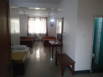 a living room with chairs and tables and a window at MYSORE MAHALAKSHMI ROOMS in Mysore
