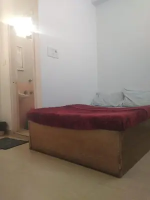 a bed in a room with a red blanket on it at MYSORE MAHALAKSHMI ROOMS in Mysore