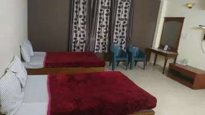 a hotel room with two beds and a table and chairs at MYSORE MAHALAKSHMI ROOMS in Mysore