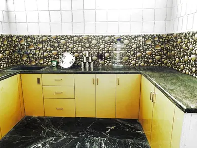 a kitchen with yellow cabinets and a tiled wall at Mannat Inn TS Mysore - Family Homestay in Mysore