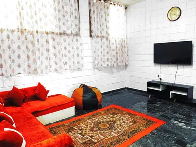 a living room with a red couch and a flat screen tv at Mannat Inn TS Mysore - Family Homestay in Mysore
