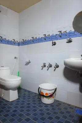 a bathroom with a toilet and a sink and a bucket at Villa in the woods in Trichūr