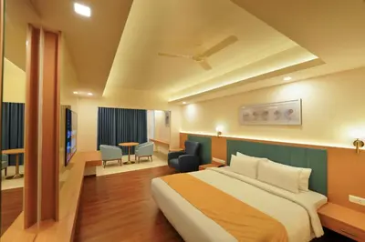 a hotel room with a bed and a table and chairs at Hotel Turmeric in Erode