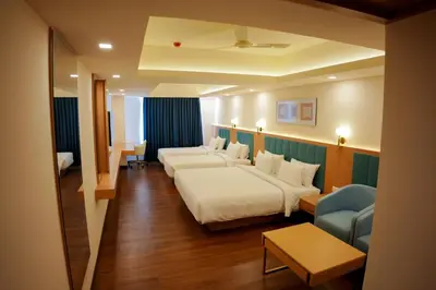 a hotel room with two beds and a couch at Hotel Turmeric in Erode