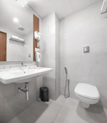 a white bathroom with a sink and a toilet at Hotel Turmeric in Erode