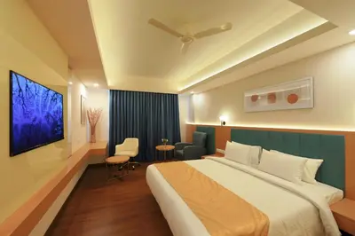 a hotel room with a large bed and a table at Hotel Turmeric in Erode