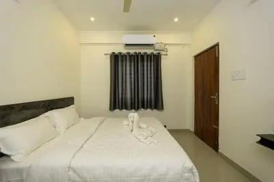 a bedroom with a bed with white sheets and a window at Fortune Inn in Erode