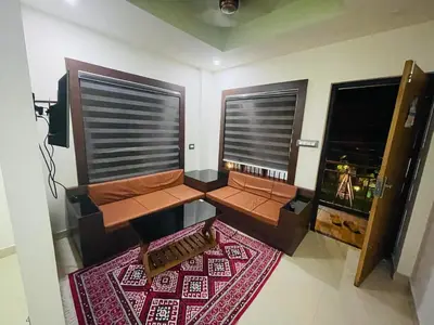 a living room with two windows and a red rug at MEDURE International in Kottakkal