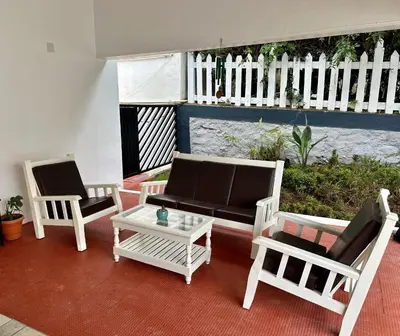 a patio with three chairs and a couch and a table at Hoopoe House, Ooty in Ooty