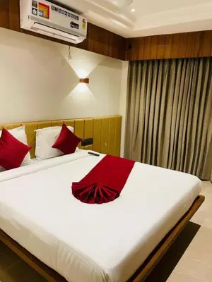 a bedroom with a large white bed with red pillows at Hotel Emora Tree in Mysore