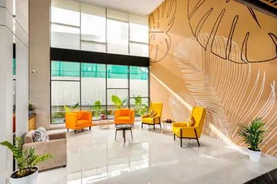 an office lobby with orange chairs and a wall of windows at PRESIDENCY AIRPORT HOTEL in Cochin