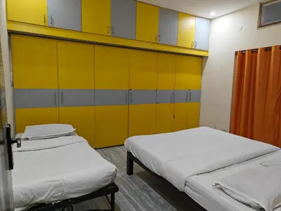 two beds in a room with yellow cabinets at 2Bhk holiday home in Mysore