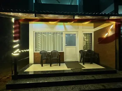 a small house with chairs in front of a door at Coorg Jungle Mist in Madikeri