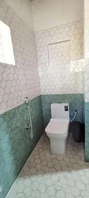 a bathroom with a toilet in a green and white wall at xplorest in Mysore