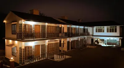a large building with a balcony at night at Moon Wings Mountain Resort in Kanthalloor