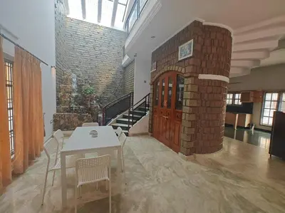 a room with a table and chairs and a brick wall at Waterfall Villa - 4BHK in Mysore