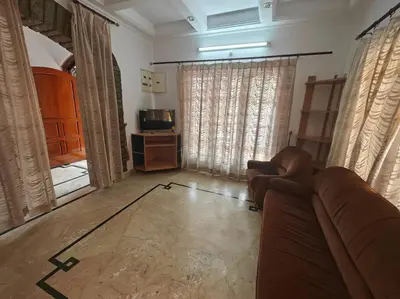 a living room with a couch and a television at Waterfall Villa - 4BHK in Mysore