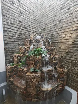 a stone wall with a waterfall in the middle at Waterfall Villa - 4BHK in Mysore